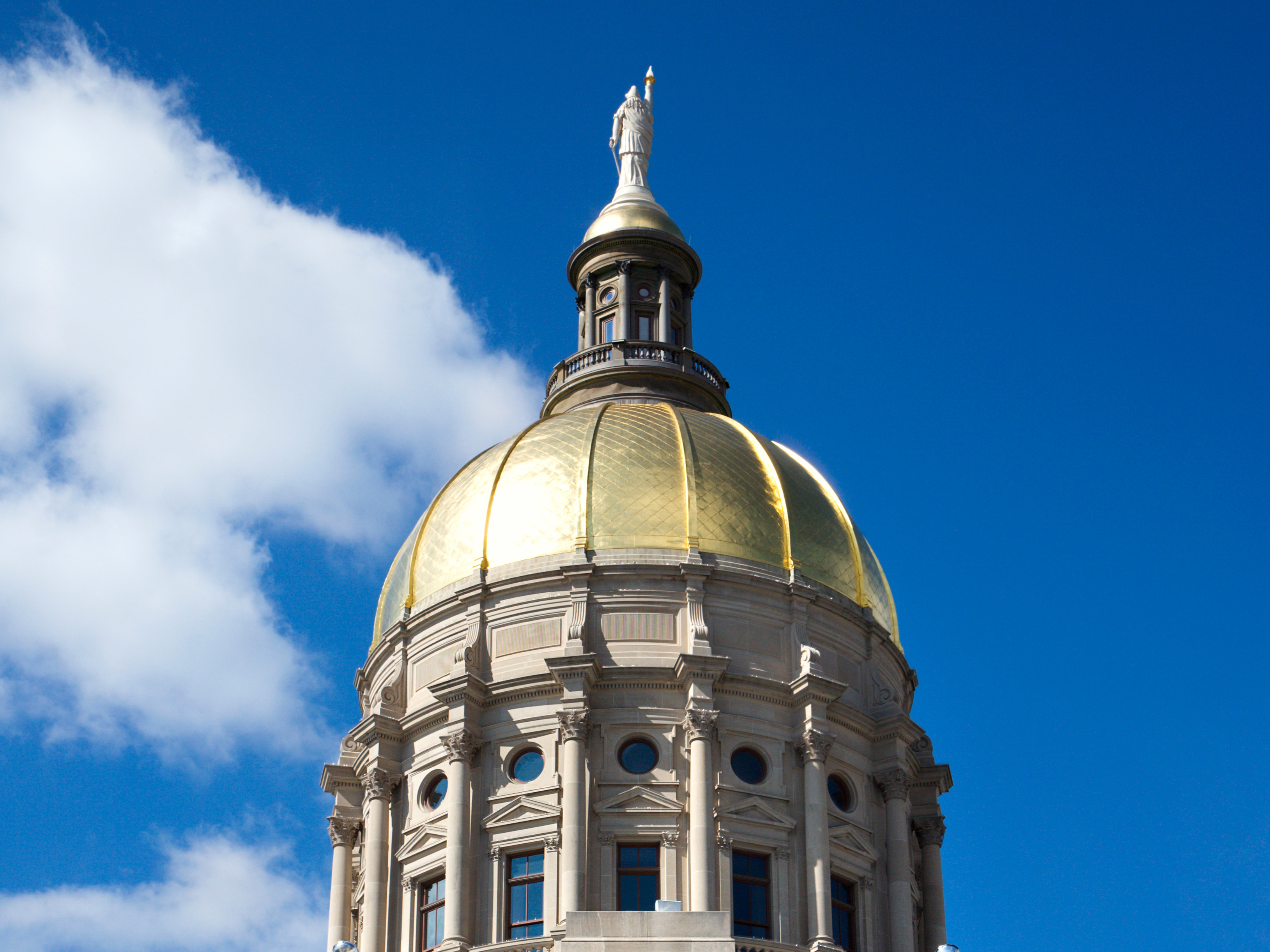 Exterior of Georgia Capitol building featuring the gold dome on a blue sky.