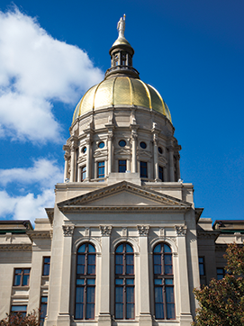 The gold dome of the Georgia capitol building against a blue sky with some white clouds.