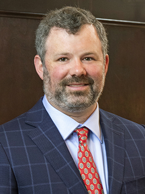 A smiling man with a beard wearing a suit and tie.