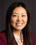 A woman wearing a burgundy suit jacket and an ivory blouse.